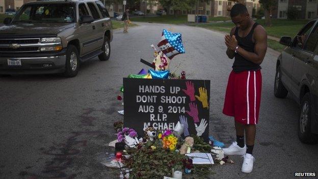 Ken Kendricks Jr., a nearby resident, puts his hands together in prayer at a makeshift memorial at the site where unarmed teen Michael Brown was shot dead in Ferguson, Missouri 22 August 2014