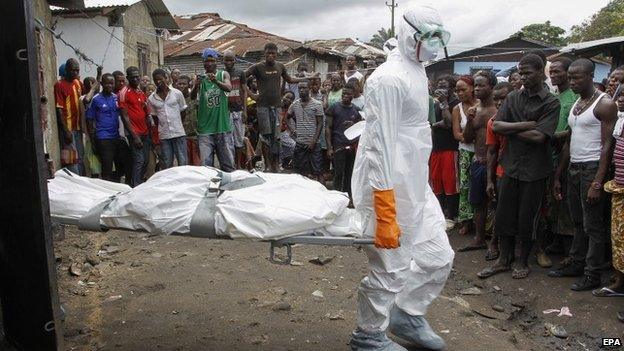 A Liberian burial squad carries the body of a suspected Ebola victim in the slum area of Logan Town outside Monrovia, Liberia, 30 September 2014.
