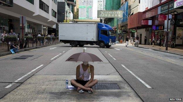 A protester sits under an umbrella as he attends a rally along a main street at Hong Kong's shopping district Tsim Sha Tsui October 1, 2014.