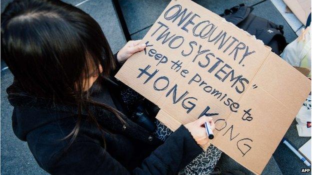 Woman writes a sign supporting Hong Kong at a protest in Stockholm, Sweden (1 Oct 2014)