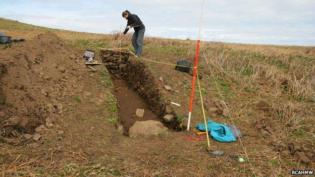 Recording the excavation trench through a cooking mound of burnt stones on Skomer Island