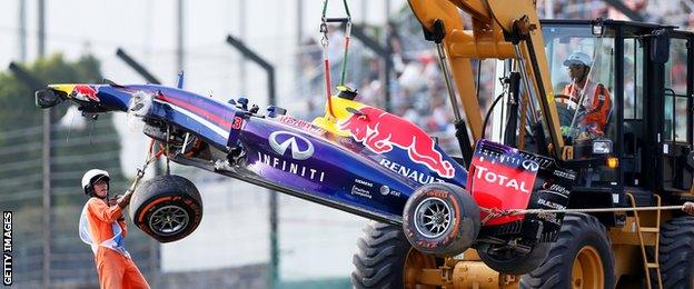 Marshalls remove the wrecked car belonging to Daniel Ricciardo of Australia and Infiniti Red Bull Racing during practice for the Japanese Formula One Grand Prix at Suzuka.