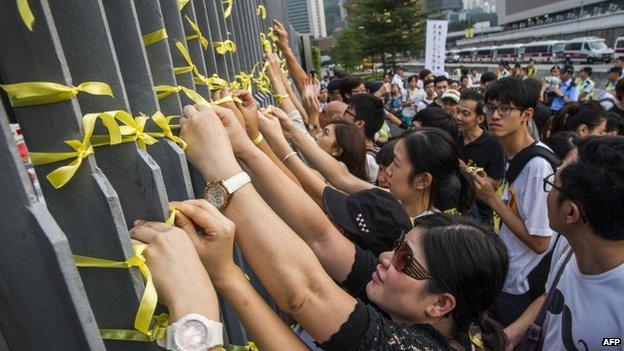 Students in Hong Kong attach yellow ribbons to the barriers fences of government offices as they protest for greater democratic rights on 24 September 2014