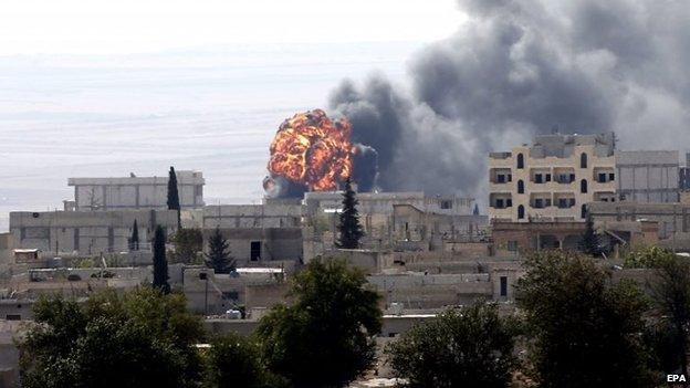 Flames and smoke rise from a building in the Syrian town of Kobane after it is hit by shellfire (3 October 2014)