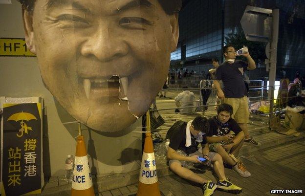 Protesters gather in the streets outside the Hong Kong Government Complex next to a cardboard poster of C.Y.Leung, Hong Kong"s Chief Executive on 30 September 2014