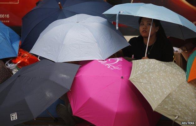 A protester sits under umbrellas as she blocks the main street to the financial Central district outside the government headquarters in Hong Kong, 30 September 2014.