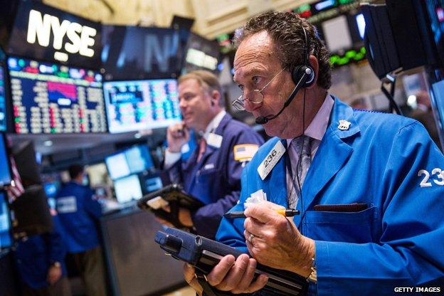 A man stands looking at computer screens at the NYSE