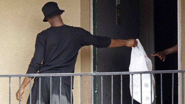 A man passes a bag, delivered by the Red Cross and the North Texas Food Bank, in to the apartment unit at The Ivy Apartments complex where a man diagnosed with the Ebola virus was staying in Dallas, Texas 2 October2014