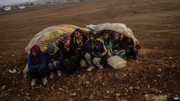 Syrian Kurds take cover from rain in Suruc after crossing border between Syria and Turkey 30 Sept 2014