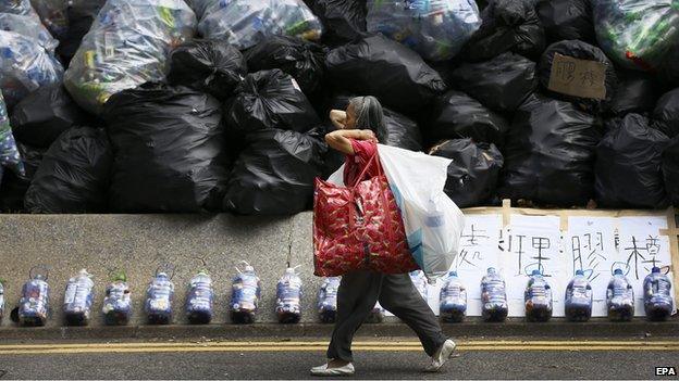 A woman walks in front of rubbish bags by govt HQ 1 October 2014