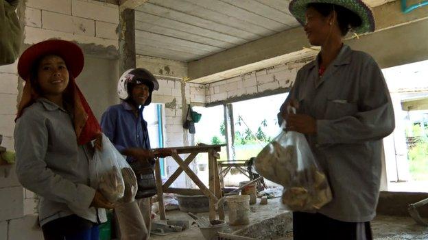 Than Wai Aung sells mushrooms to some construction workers