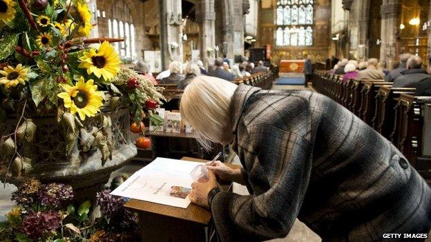 A woman signs the book of condolence at Eccles Parish Church