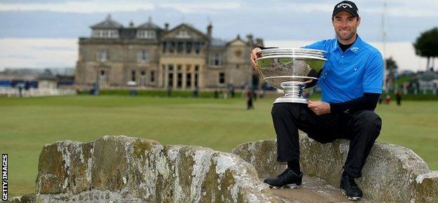 Oliver Wilson of England holds the trophy aloft on the Swilcan Bridge on the 18th hole