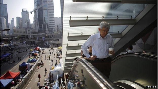 Government employees arrive to work as they walk along an area occupied by protesters outside of the government headquarters building in Hong Kong 6 October 2014