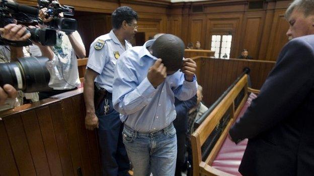 Zola Tongo (C), one of three people originally charged with the Anni Dewani"s killing, covers his face as policemen escort him to the Cape Town High Court, on 7 December 2010 in Cape Town