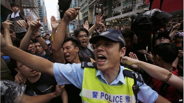 A police officer tries to hold back pro-democracy student protesters during a clash local residents in Mong Kok, Hong Kong, Saturday, 4 October 2014