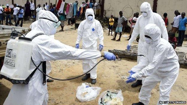 Red Cross employees in Liberia disinfect themselves