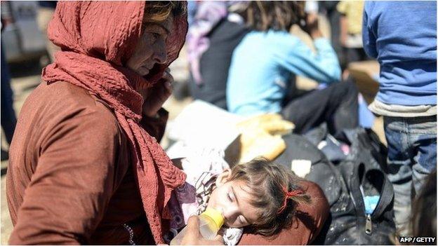 A Syrian Kurd woman feeds a child after they crossed the border between Syria and Turkey near the southeastern town of Suruc on 20 September 2014.