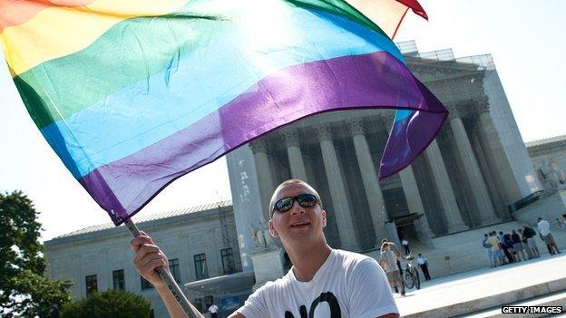 A man waves a gay pride flag in front of the US Supreme Court building.