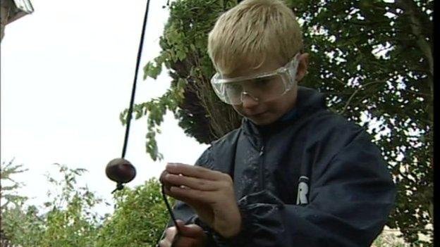 A boy has a conker fight wearing goggles