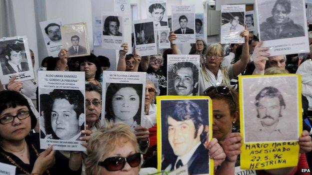 Relatives of victims of forced disappearance during the dictatorship period show photographs after learning of the sentence against former dictator Reynaldo Bignone in Buenos Aires on 7 October 2014