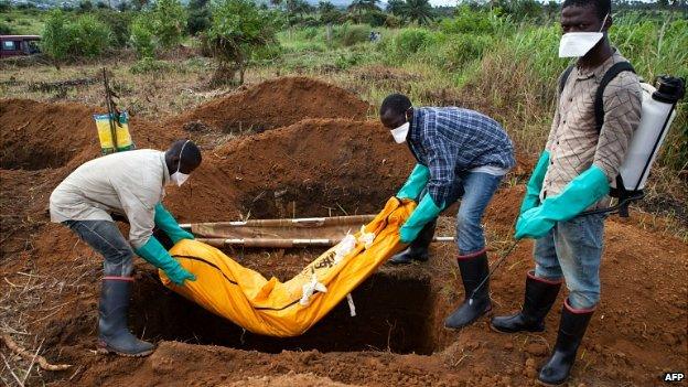 Volunteers in protective suit bury the body of an Ebola victim in Waterloo, 30km southeast of Freetown, Sierra Leone - 7 October 2014