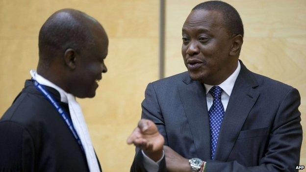 Kenya's president Uhuru Kenyatta talks to a member of his defence team at the International Criminal Court in The Netherlands on 8 October 2014