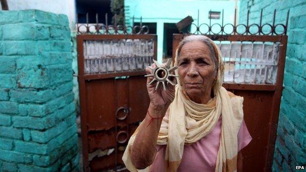 An Indian villager displays parts of mortar shells allegedly fired from the Pakistani side of the disputed Kashmir border, at Arnia Village