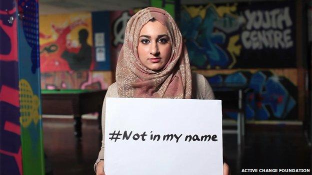 woman holding #notinmyname placard