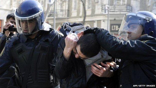 Two policemen lead away a protester in Baku in Azerbaijan