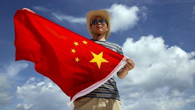 Police officer poses with a Chinese national flag on the Quanfu island.