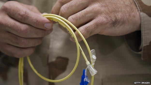 A man holding one of the feeding tubes used for detainees