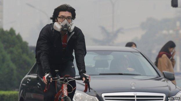 Cyclist wearing respiratory mask on the streets of Beijing (10 October)