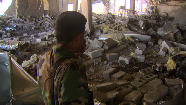 A Kurdish fighter stands amidst debris at the Rabia hospital