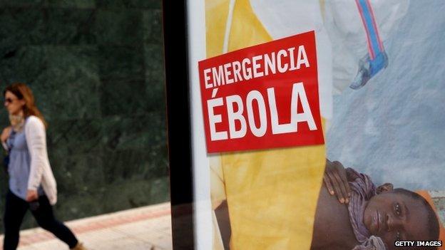 A woman walks past a bus stop banner reading "Emergency Ebola" near Madrid, Spain. Photo: 9 October 2014