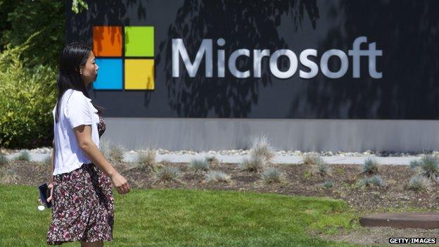 A woman walks in front of a Microsoft sign on the company's Washington campus.