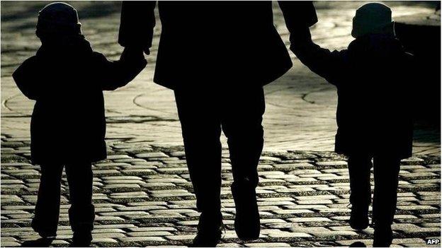 A silhouette of an adult walking holding hands with two young children