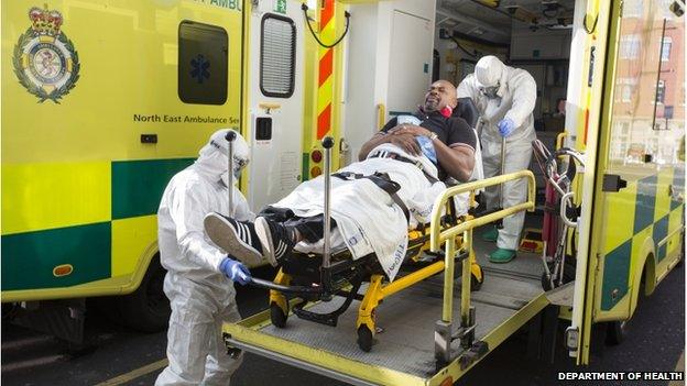 An actor playing an Ebola patient is taken out of an ambulance