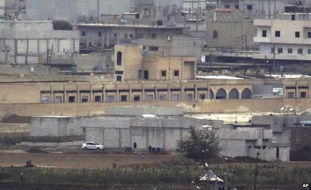 Islamic State gunmen crouch during fighting in Kobane, 11 October (photo taken with long-range lens)