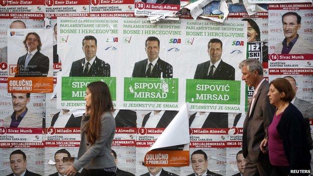 People walk past election posters in Sarajevo, October 10, 2014