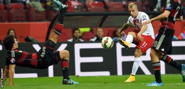 Poland's midfielder Kamil Grosicki shoots past Germany's Mats Hummels and Christoph Kramer