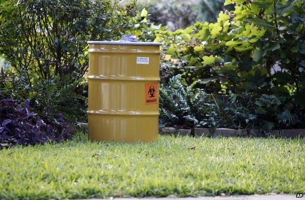 A barrel labelled "biohazard" stands on a lawn outside the apartment complex of the infected health worker in Dallas, 12 October