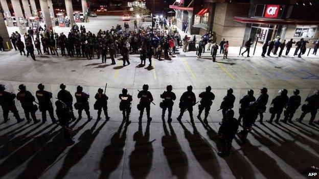 Police officers in riot gear hold a line as they watch demonstrators in St Louis, Missouri, 12 October 2014