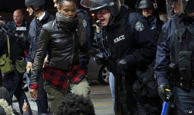 A police officer dressed in riot gear gives the final warning to move or be arrested to a group of roughly 50 protesters conducting a sit-in at a QuikTrip in St Louis, 12 October 2014