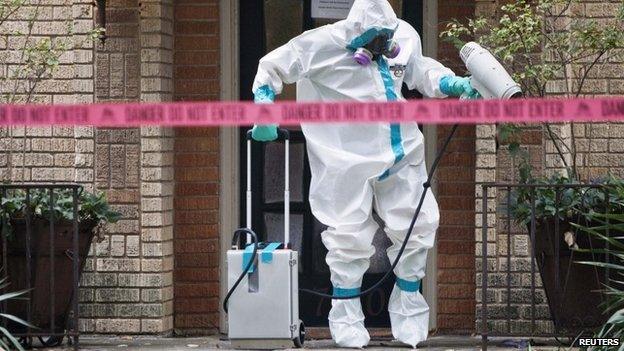 A member of the CG Environmental HazMat team disinfects the entrance to the residence of a health worker at the Texas Health Presbyterian Hospital who has contracted Ebola in Dallas, Texas, 12 October 2014