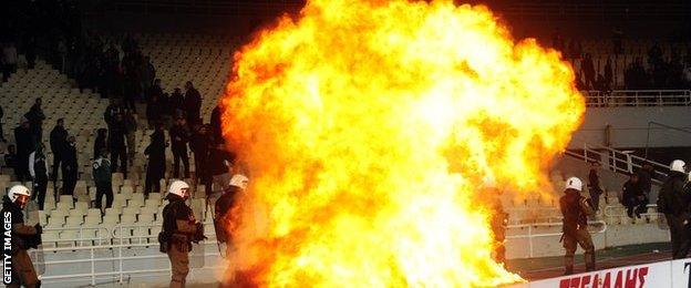 Greek riot police watch a fire set off by a petrol bomb as they clash with Panathinaikos supporters during a Greek Super League football game against Olympiakos in Athens in March 2012