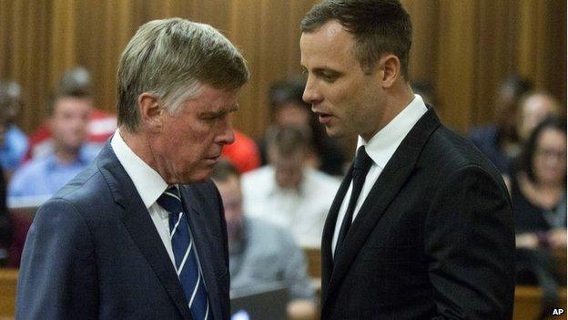 Oscar Pistorius talks with one of his defence lawyers in Pretoria, South Africa 13 Oct 2014
