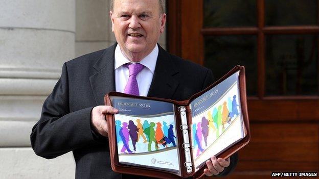 Irish Finance Minister Michael Noonan poses for pictures with the Irish 2015 budget outside the government buildings in Dublin