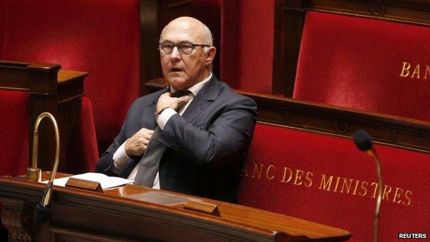 French Finance Minister Michel Sapin adjusts his tie at the start of budget debates in the National Assembly. Photo: 14 October 2014