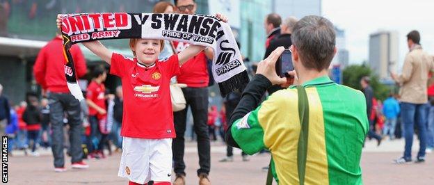 A young Manchester United fan poses for a photo outside Old Trafford